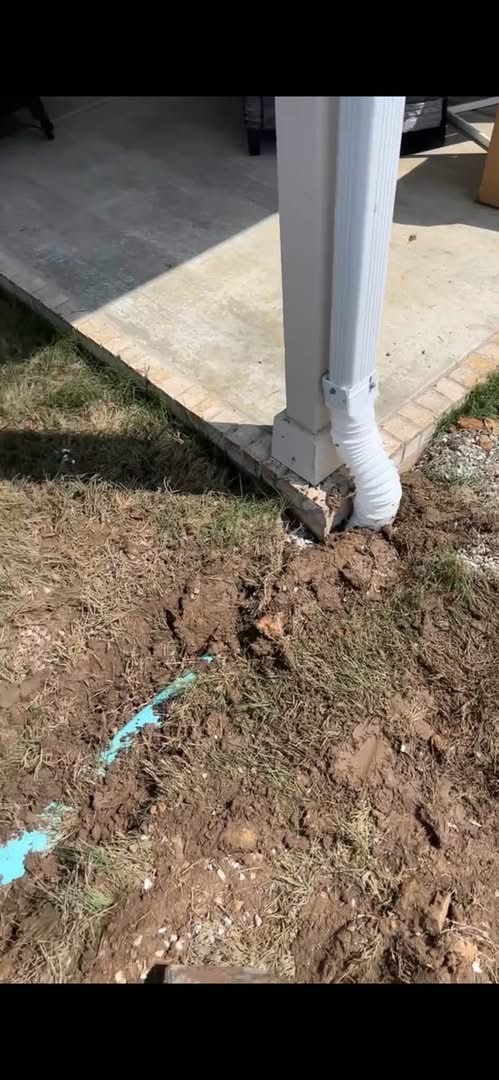 Utility Locate & Trench — Marked line and trench work at a covered patio downspout.